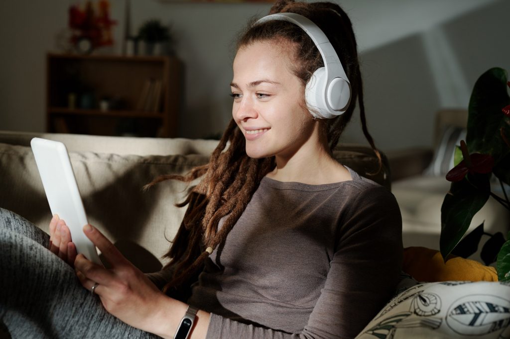 Girl with headphones holding tablet in front of herself while watching movie
